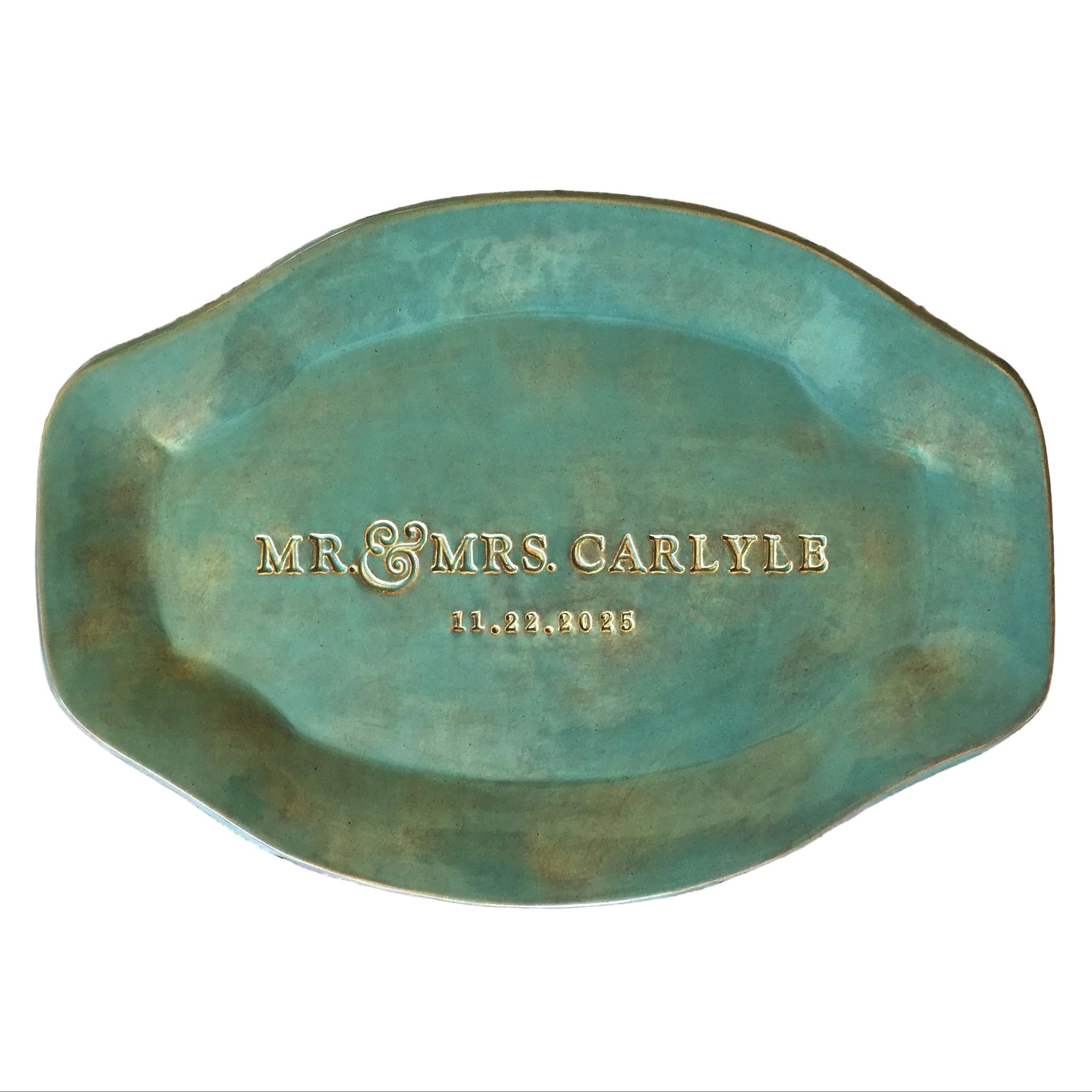 Handmade ceramic rustic green round platter with handles has gold typographic design pressed in clay, dish on wood surface. Dish has Mr & Mrs family name and a date. Unique personalized kitchen wedding gift, anniversary plate keepsake for couple, friends and family life event memorial celebration. 