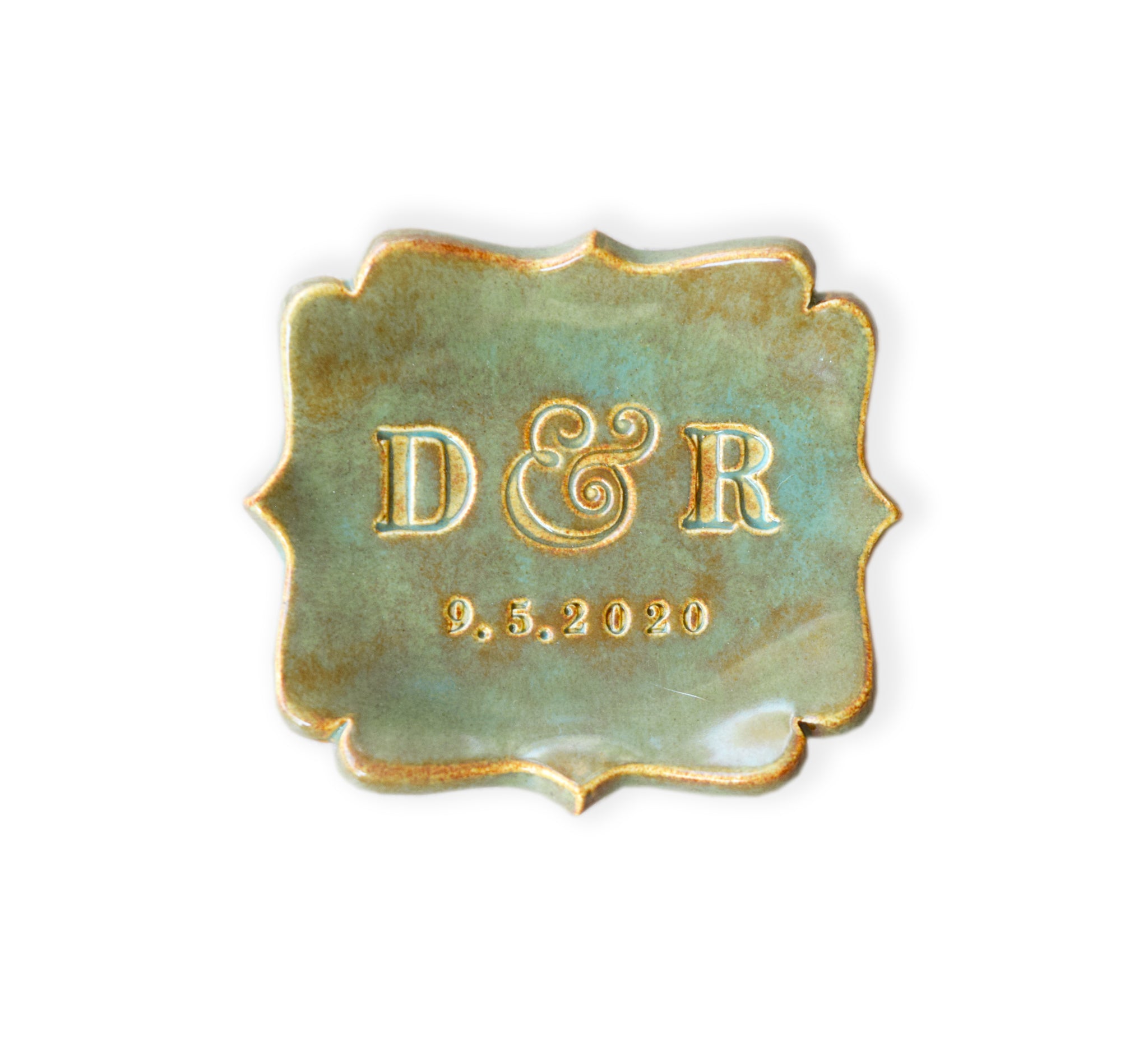 rustic green fancy square handmade ceramic decorative tray with scalloped curvy sides and gold rim accents, dish is on white surface, typographic design includes hand stamped personalization: 2 name initials and a date. Name initials and date are accented in gold, customized wedding ring dish couple anniversary plate, jewelry holder