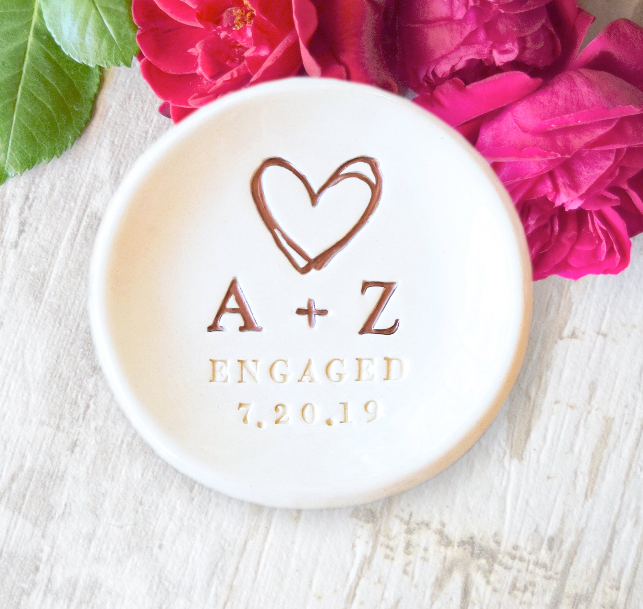 Handmade ceramic ring dish personalized with couple’s name initials and engagement date, features hand painted rose gold heart and initials, custom engagement gift for couple