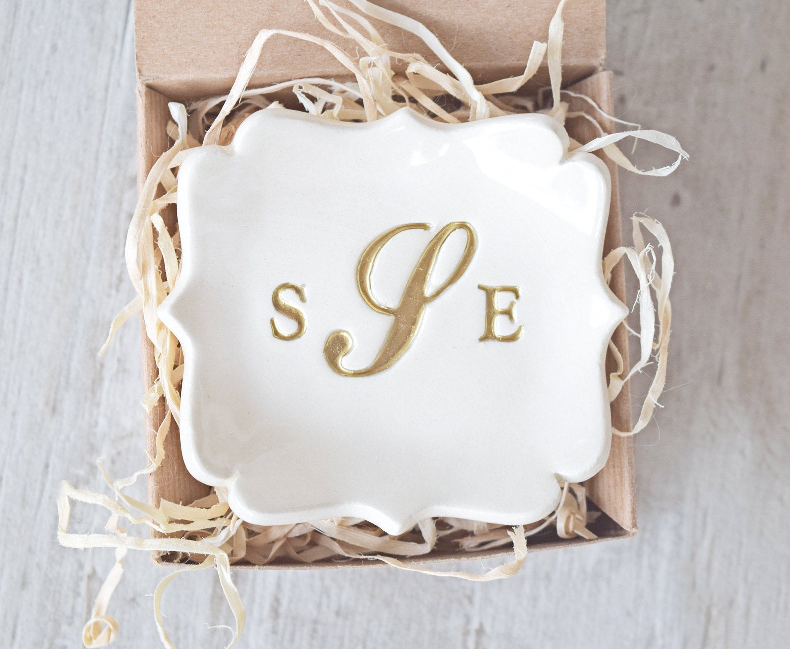 Handmade ceramic decorative pottery tray is abstract square personalized jewelry holder custom monogram ring dish with gold 3 letter typographic design in a gift box. Custom wedding ring tray for couple or individual keepsake with 3 name initials pressed in clay. Middle letter is fancy calligraphy. All letters are painted gold. Ideal just married gift for newlyweds couple home or wife anniversary gift to hold rings, earrings, necklaces, bracelets.