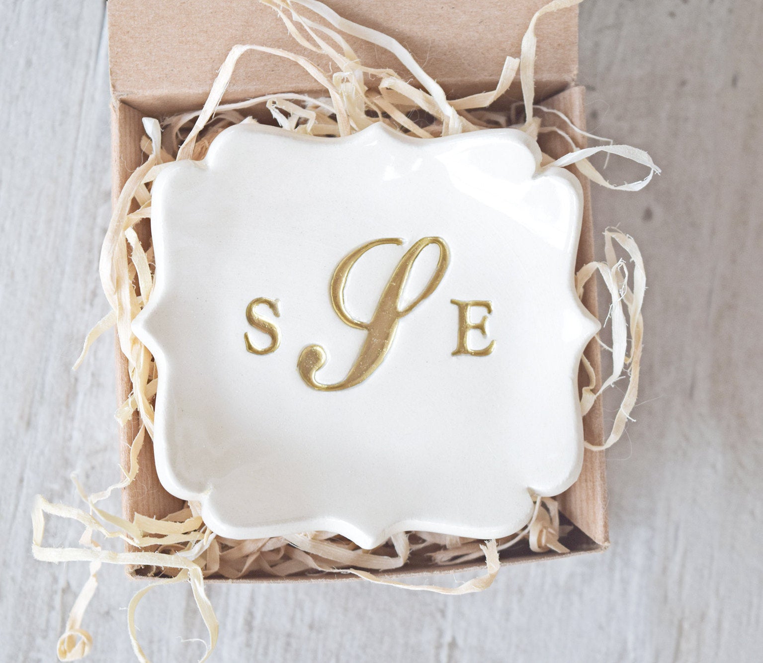 Handmade ceramic decorative pottery tray is abstract square personalized jewelry holder custom monogram ring dish with gold 3 letter typographic design in a gift box. Custom wedding ring tray for couple or individual keepsake with 3 name initials pressed in clay. Middle letter is fancy calligraphy. All letters are painted gold. Ideal just married gift for newlyweds couple home or wife anniversary gift to hold rings, earrings, necklaces, bracelets.